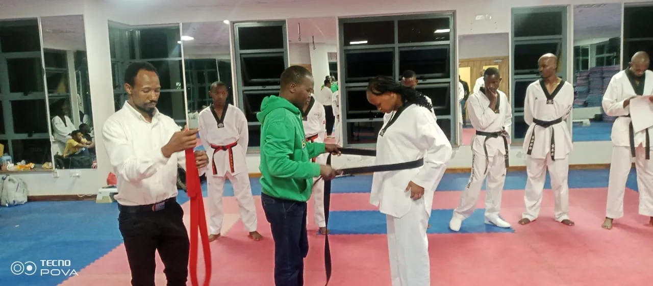 Athlete receiving a taekwondo belt during a promotion ceremony
