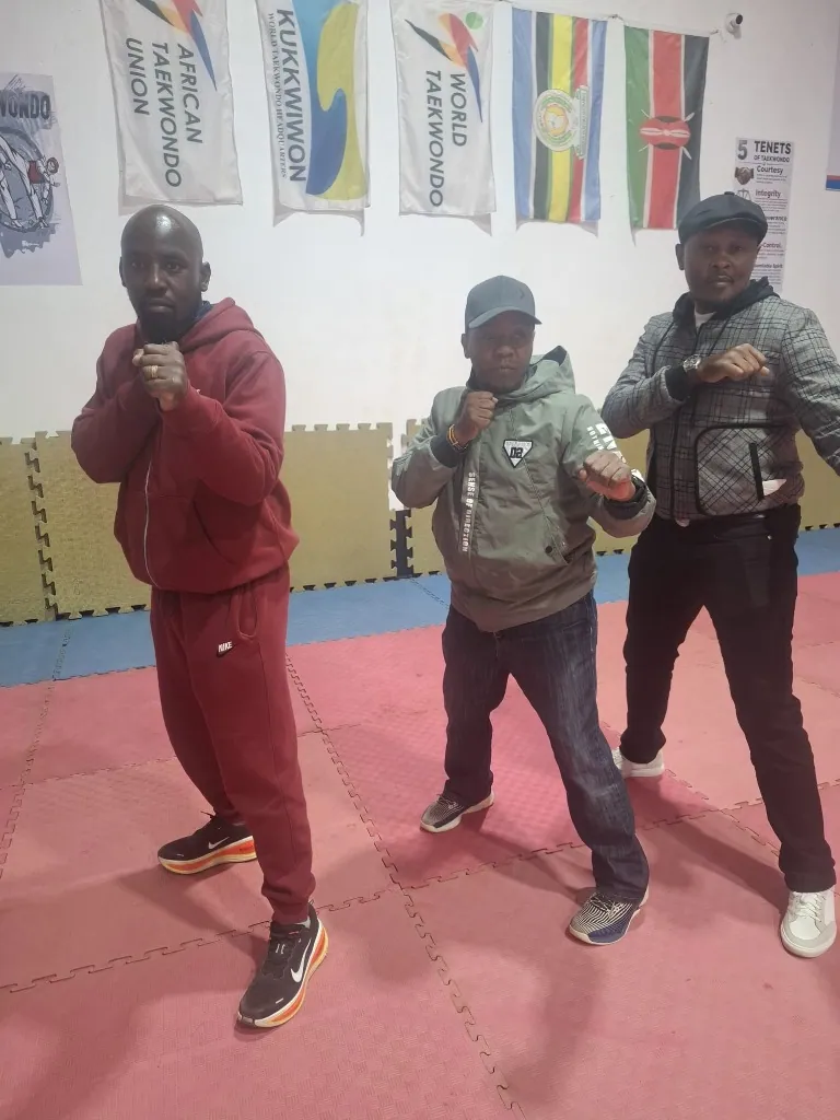 Three taekwondo coaches standing together in the dojang